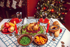 圣诞节晚餐烛光，表设置。在一间有一棵圣诞树的装饰房间的烤火鸡的感恩节表.