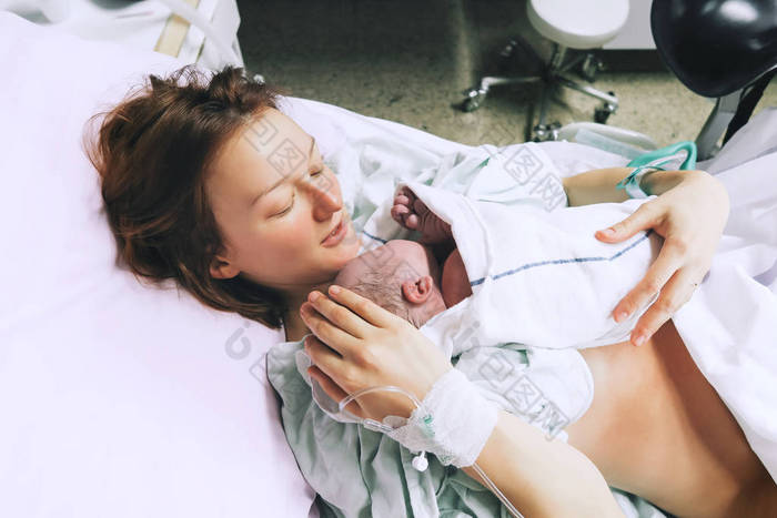 妈妈抱着她刚出生的婴儿在医院分娩后