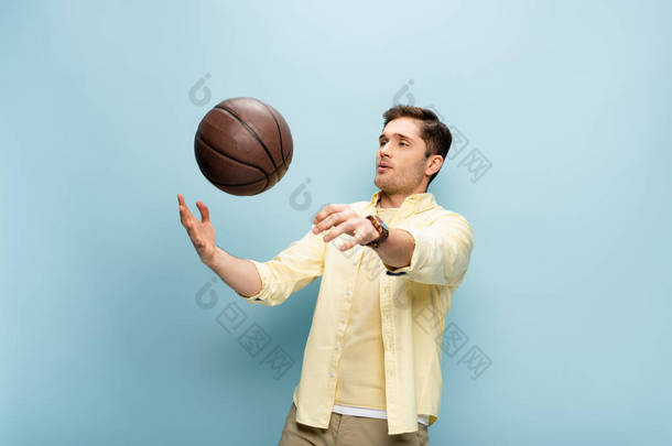 身穿黄色衬衫的人把篮球抛向蓝天