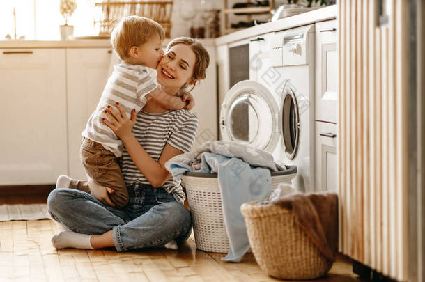 快乐的家庭母亲、家庭主妇和孩子都在洗衣机里洗衣服