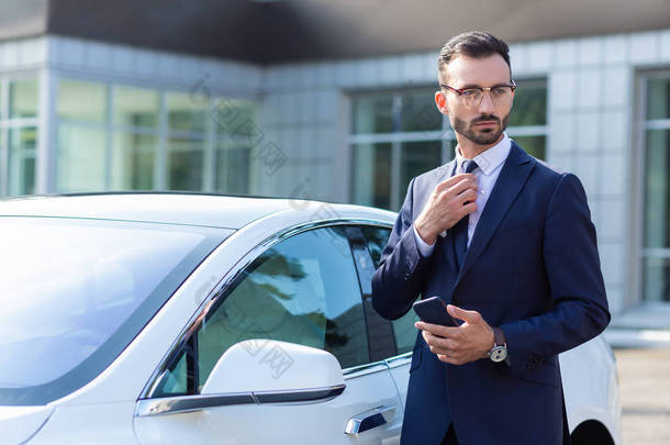 戴着眼镜的富商站在他的车旁
