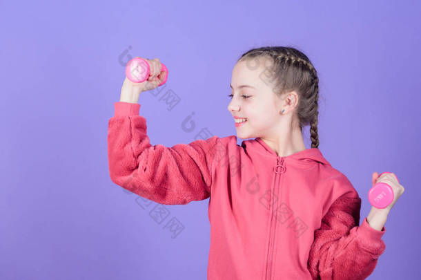 锻炼小女孩举行哑铃。健康的健身饮食。肌肉的举重。童年活动。运动成功。愉快的儿童运动员与杠铃。健身俱乐部。运动和健身