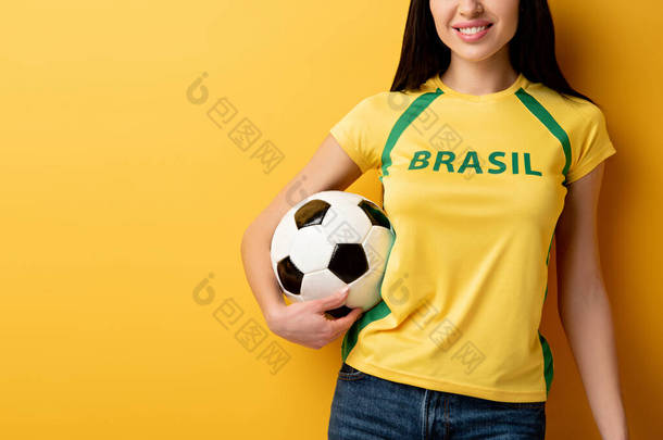 笑着的女足球迷拿着黄色球的剪影