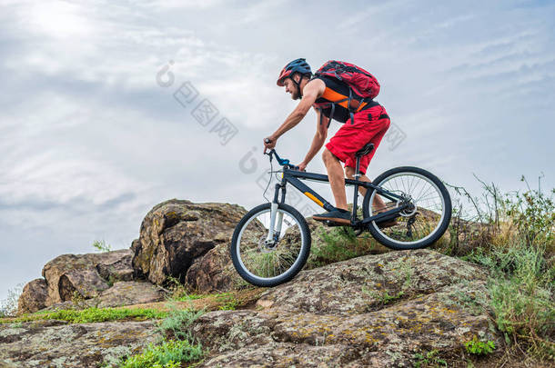骑自行车的人顺着山上的石头往下走, 这是一种积极的生活方式。极端骑自行车对蓝天, 自由空间, 为您的文本.
