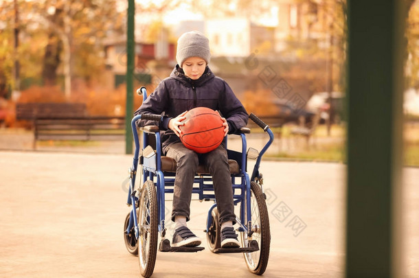 小男孩在轮椅与球在操场
