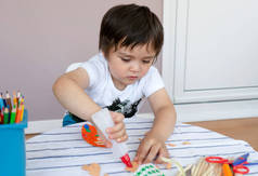  制作复活节贺卡的小男孩；儿童桌上的艺术创作材料；3岁男孩粘在彩纸上；与父母一起在幼儿园进行手工艺活动；家庭教育概念