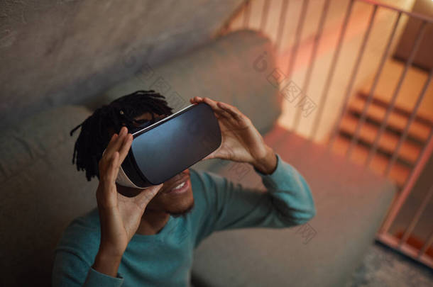 非洲裔美国人穿着VR装备，沉浸在未来派的内部体验中，有着很高的视角，复制空间