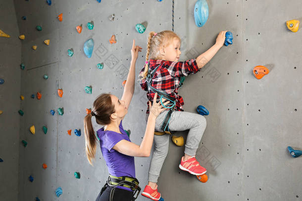 帮助小女孩在健身房爬墙的教练