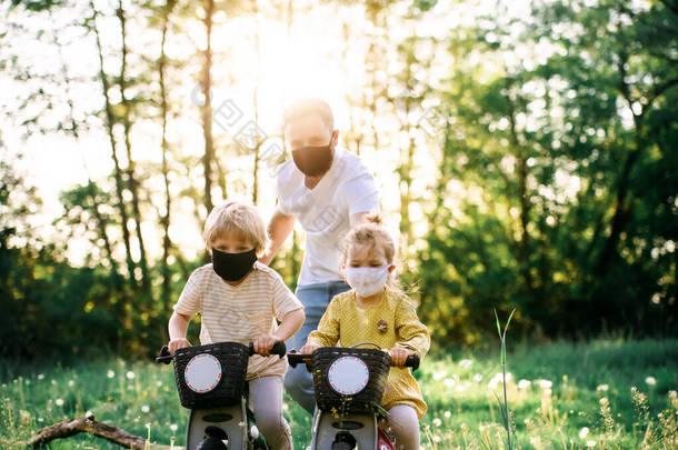 父亲带着两个小孩，在大自然中骑车旅行时戴着面具.