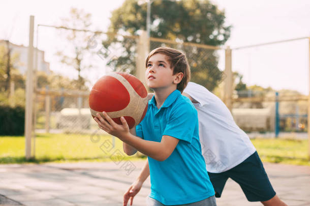 两个少年在操场上打篮球.运动员在<strong>比赛</strong>中为争取球而奋斗.健康的生活方式、运动、动机