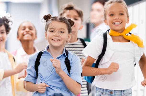 兴奋的多文化学童沿着学校走廊奔跑的全景照片