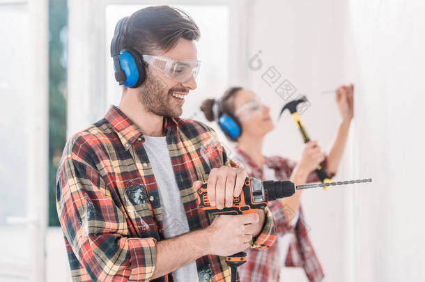 快乐的年轻人在房屋维修过程中使用电钻
