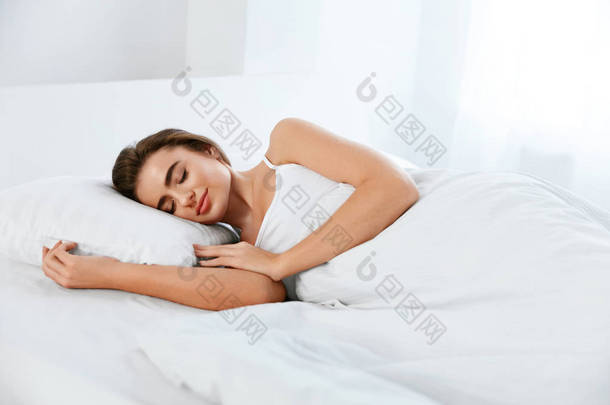 白色床上用品。睡在床垫上的女人, 床上柔软的枕头。高分辨率.
