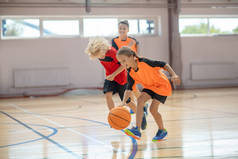 穿着鲜艳运动服的孩子们在体育馆打篮球