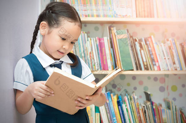 图书馆里的亚洲学生可爱的女孩阅读本书 