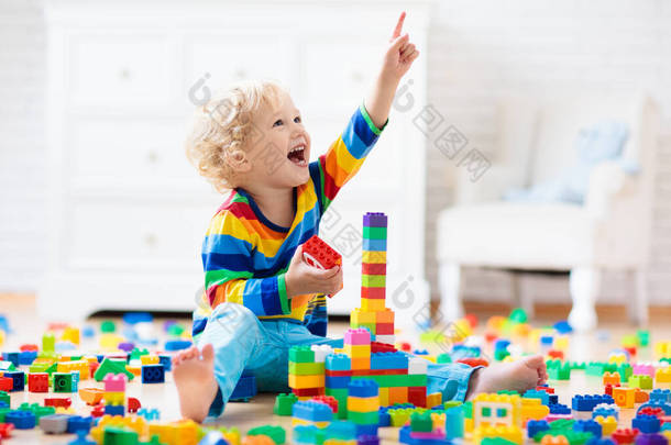 孩子们玩五颜六色的玩具块.小男孩在家里或托儿所建塔。幼儿教育玩具。婴儿或幼儿的建筑块。幼稚园游戏室的烂摊子.