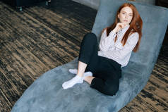 红头发的年轻女子躺在扶手椅上，向心理治疗师讲述问题的头像.
