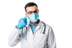 头戴医用口罩，身穿白色外套的医生，使用在白色隔热板上隔热 