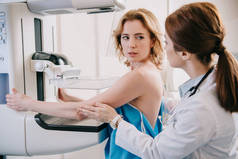年轻放射学家帮助病人准备X光机上的乳房X光诊断