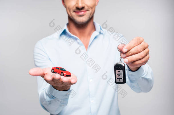 微笑的成人男子抱着汽车报警<strong>遥控</strong>和<strong>玩具</strong>红色汽车查出白色的短款镜头