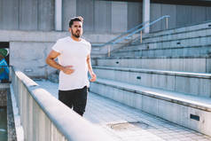 在城市环境下跑步的白人健康运动员，穿着空白T恤的肌肉男，业余时间跑步