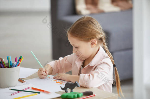 侧视图肖像可爱的小女孩画画坐在桌前独自坐在家里，复制<strong>空间</strong>