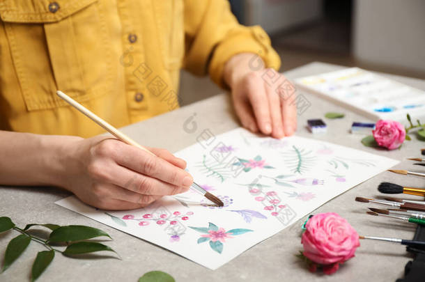 妇女在灰色石桌上画水彩画花，特写