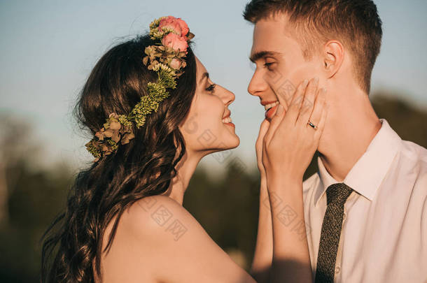 美丽快乐的年轻夫妇在公园接吻的侧面视图