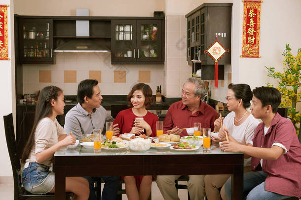 大亚洲家庭在农历<strong>新年</strong>庆祝活动中交谈和吃饭，在背景中联名祝福来年