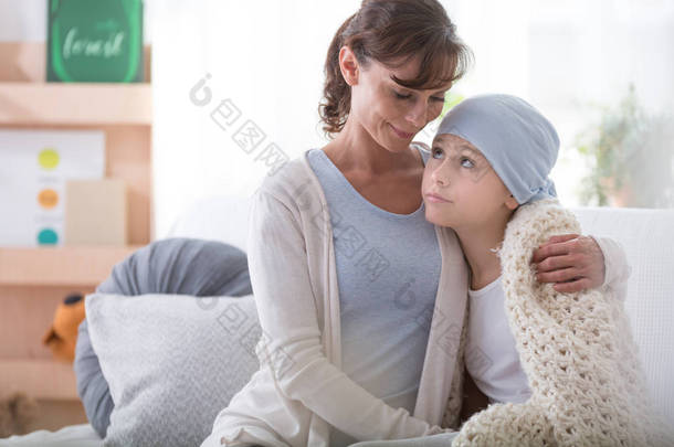 微笑的照顾者支持生病的孩子与癌症戴蓝色头巾