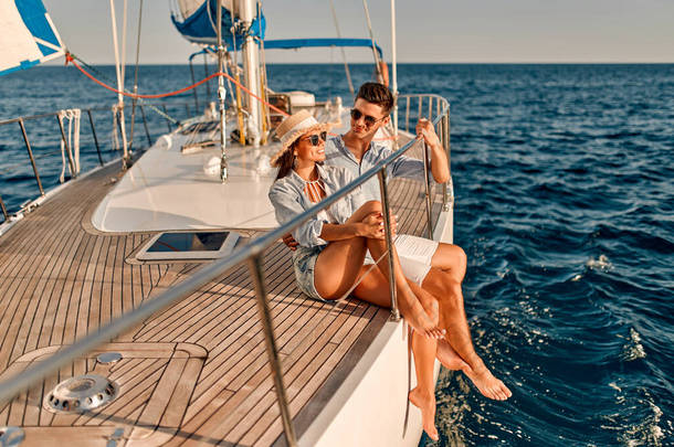 情侣们在海上航行时，坐在游艇甲板上谈恋爱。英俊的男人和漂亮的女人有浪漫的约会。奢侈旅行概念.