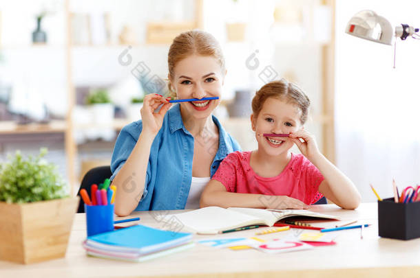 有趣的妈妈和孩子的女儿做家庭作业写作和阅读