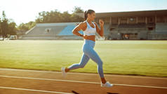身披浅蓝色运动上衣和腿的美丽健身女子在体育场慢跑。她在一个温暖的夏日午后跑得很快.运动员的日常体育锻炼.
