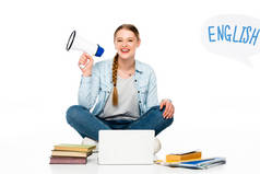 笑着的女孩坐在地板上，带着扩音器靠近笔记本电脑、书本和复印机，英语中的字母出现在白色的泡沫中