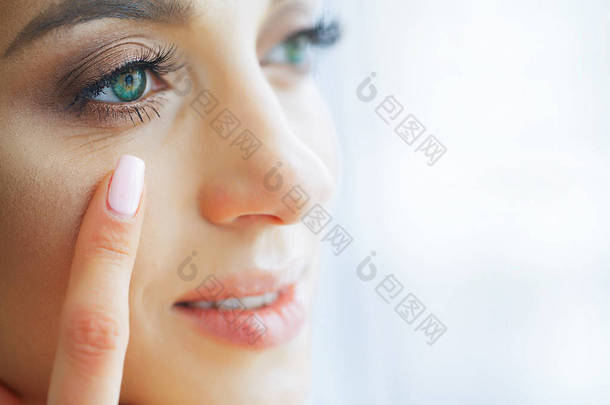 健康和美丽。美丽的年轻女孩与绿色的眼睛持有隐形眼镜在手指上。眼部护理。良好的视力新的看法。高分辨率