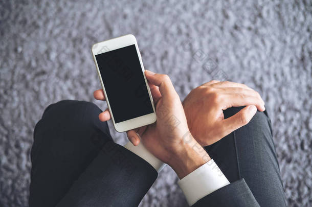一个商务男士的样机图像在背景下用灰色地毯的空白黑屏手持白色手机