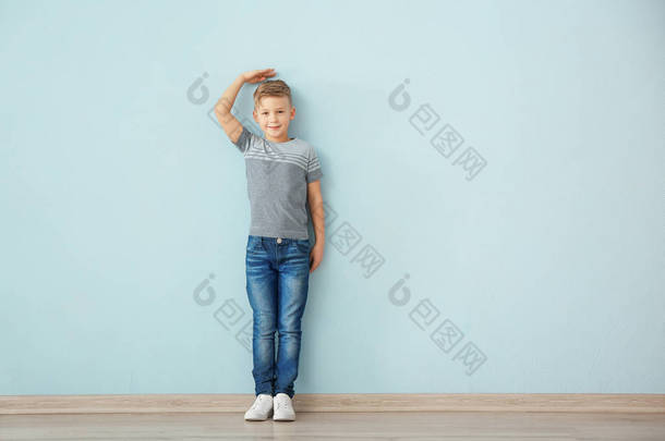 在蓝色<strong>墙</strong>壁附近测量高度的小男孩