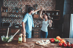 浪漫情侣在厨房做饭。英俊的男人和有魅力的年轻女人在一起做沙拉时玩得很开心。健康的生活方式概念.