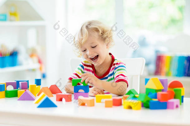 孩子玩彩色玩具块。<strong>小</strong>男孩用方块玩具建造塔楼。幼儿教育和创意玩具和游戏。婴儿在白色的卧室里用彩虹砖。在家的儿童.