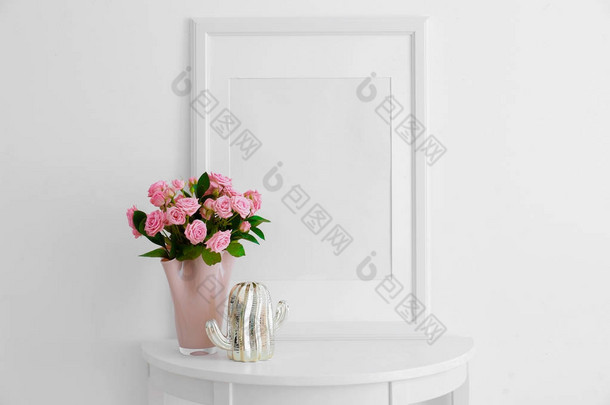空框, 粉红色的玫瑰和装饰仙人掌雕像在桌子附近的白墙