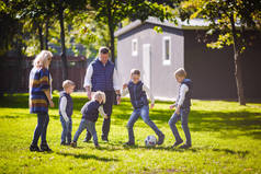 主题家庭户外活动。大友好的白种家庭六妈妈爸爸和四孩子踢足球, 运行与球在草坪上, 绿色草坪草坪附近的房子在阳光明媚的一天.