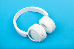 蓝色背景的无线白色耳机。音乐概念。蓝色背景耳机. 