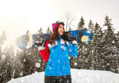 冬季在松树林的降雪中微笑的滑雪女孩