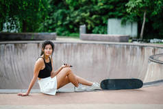 亚洲中国女孩在 skatepark 的手机和溜冰肖像