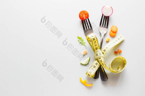叉子上的新鲜<strong>蔬菜</strong>，白色背景上的测量带，文字概念健康饮食减肥