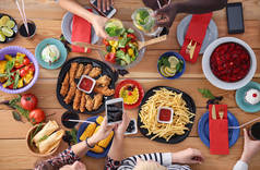 坐在木制餐桌前和一群人一起吃饭的头像。食物在桌子上。人们吃快餐.