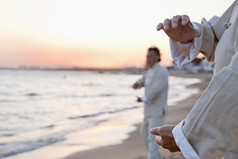 人练习太极拳在沙滩上的看日落