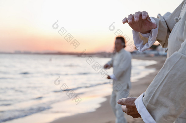 人练习太极拳在沙滩上的看日落