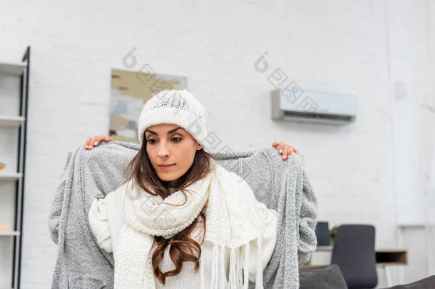 冻结年轻的妇女在家里穿暖和的衣服
