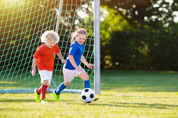 孩子们在户外球场踢足球。孩子们在足球比赛中进球。女孩和男孩踢球。在新泽西队和夹板上跑孩子学校橄榄球俱乐部。青年运动员的运动训练.